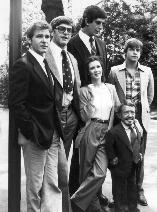 L to R: Harrison Ford (Han Solo), David Prowse (Darth Vader), Peter Mayhew (Chewbacca), Carrie Fisher (Princess Leia), Kenny Baker (R2-D2), and Mark Hamill (Luke Skywalker). Undated.